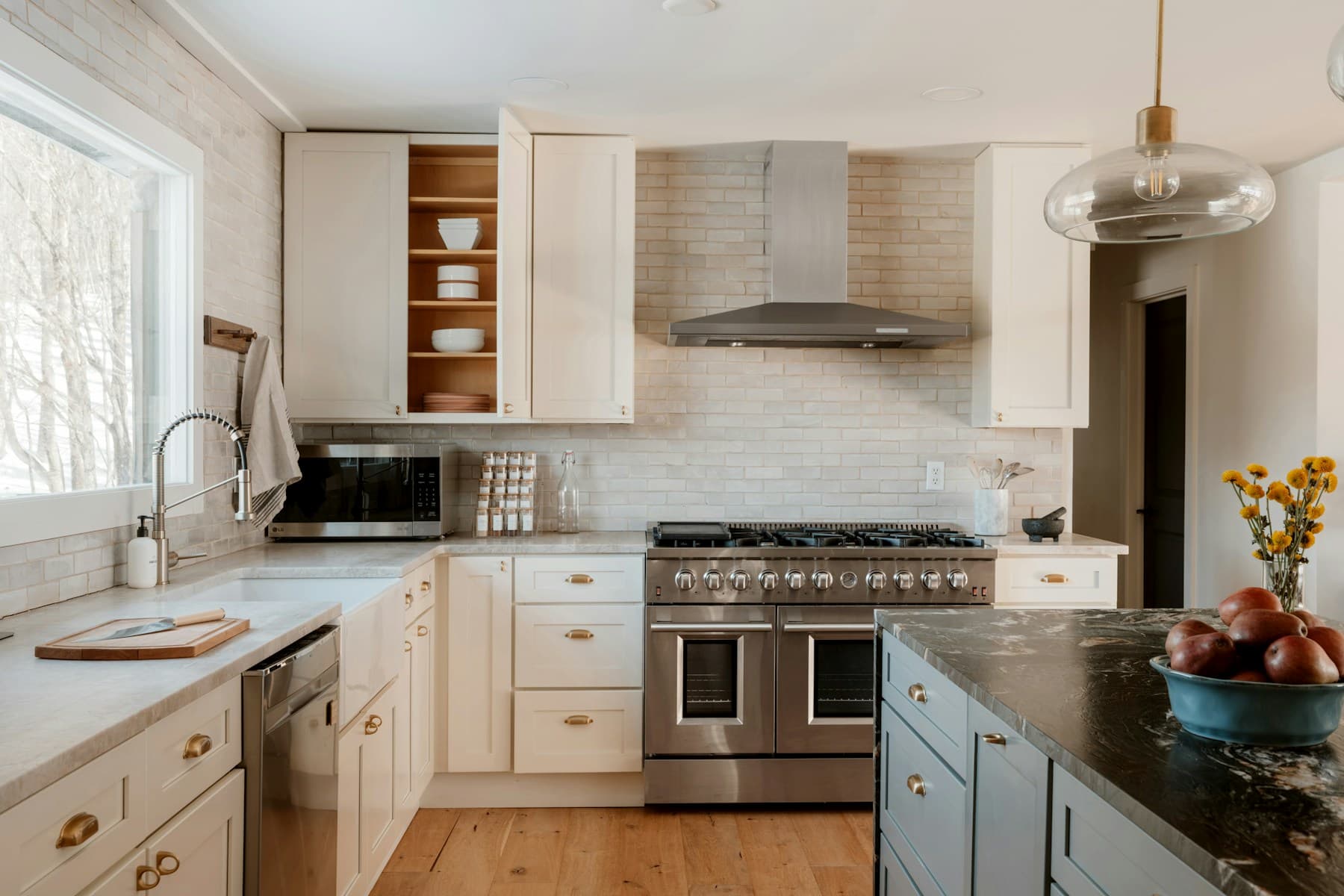 Kitchen with cream cabinets, a blue island, and stone countertops