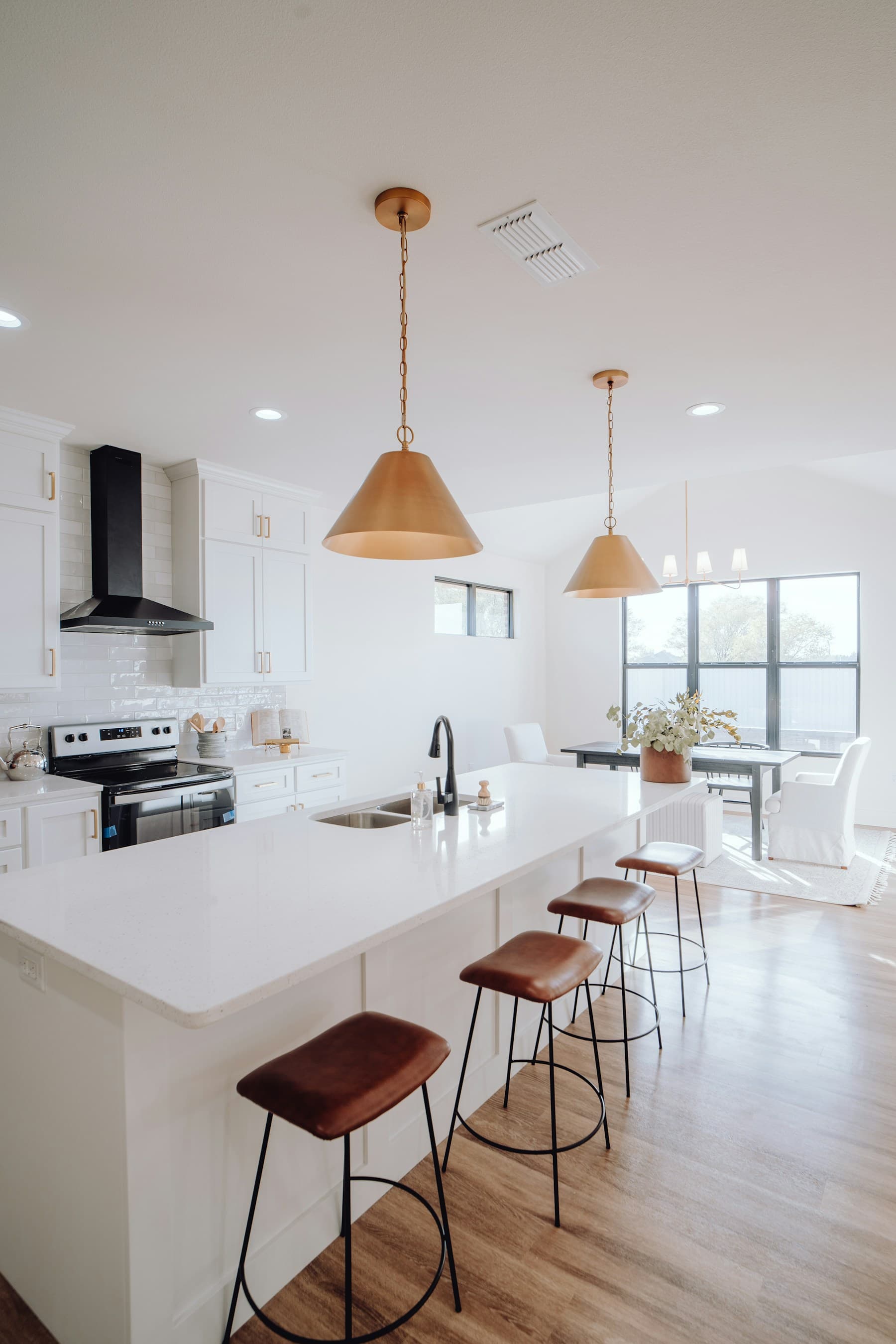 Kitchen with white shaker cabinets, brass pendants, and island seating
