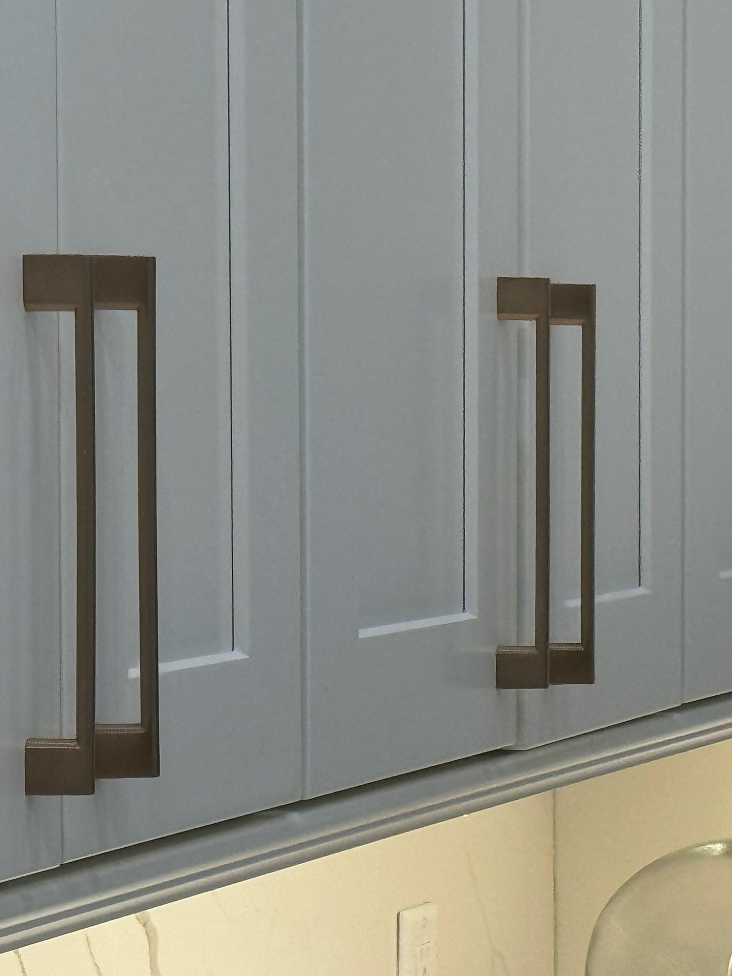 Close view of painted shaker cabinet doors with warm metal pulls