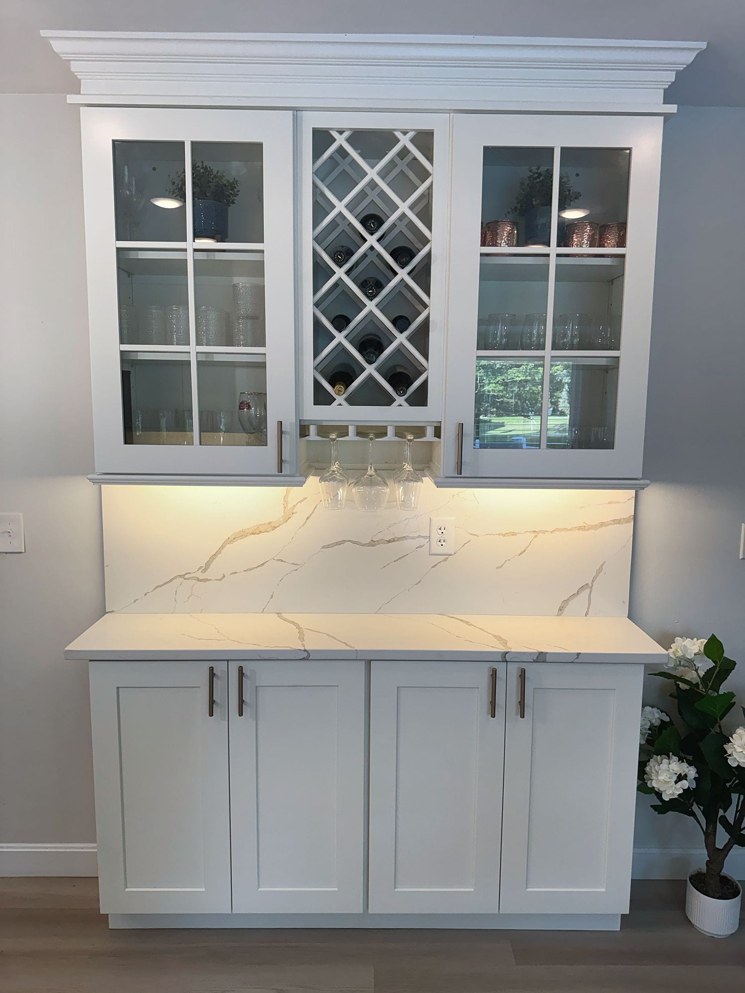 Glass-front beverage storage with a built-in wine rack, counter, and lower cabinets